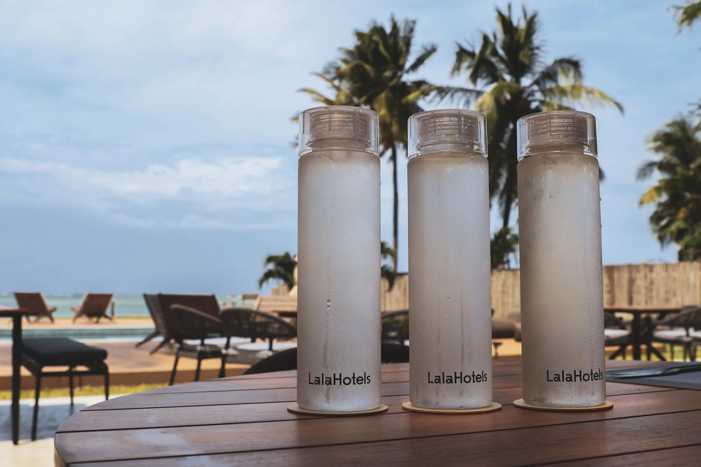 Lala Hotels reusable water bottles on a table by the pool