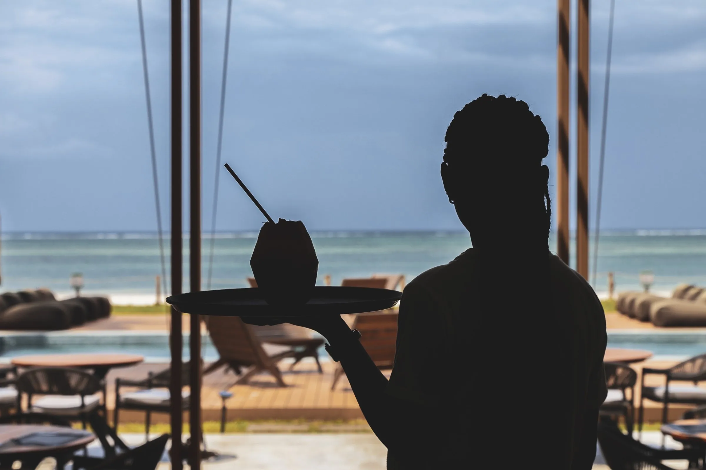 A waiter with a coconut, the sea behind