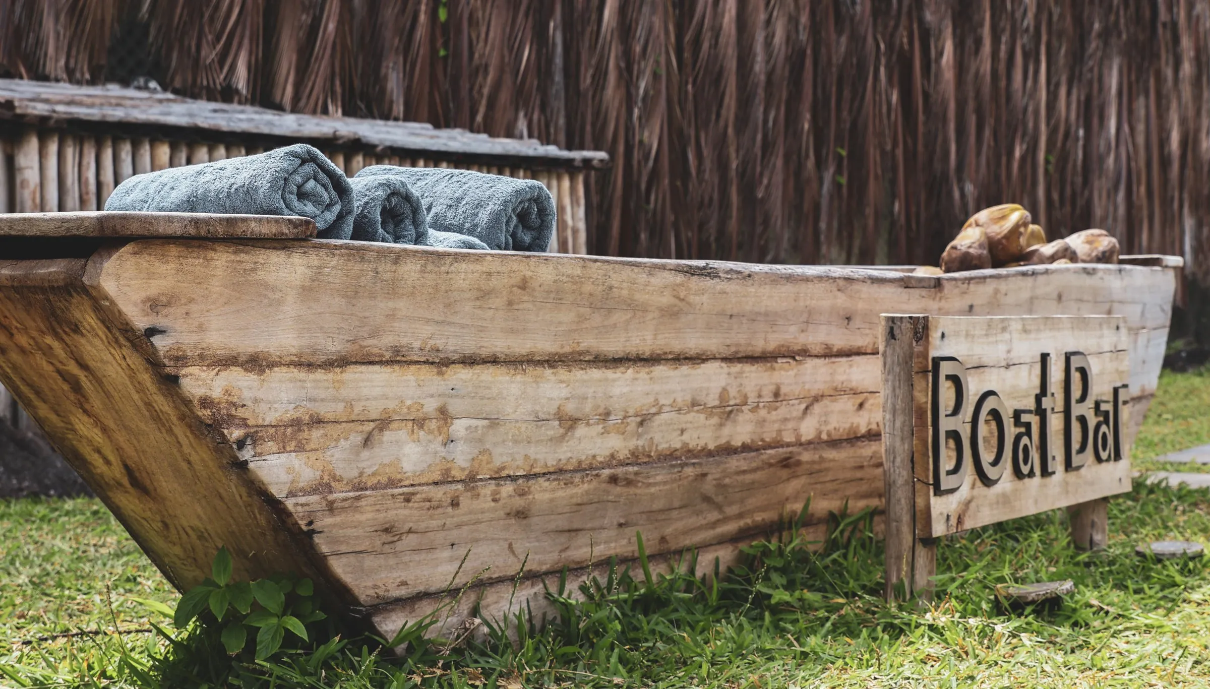 The Boat Bar: a weathered wooden boat with rolled towels, by the pool