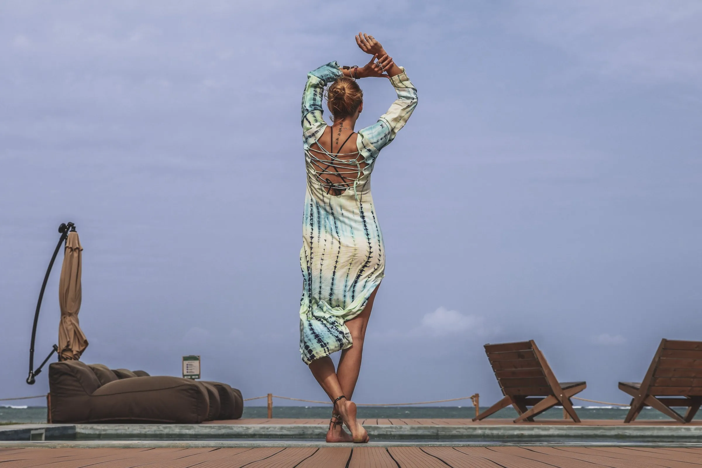 A guest on the pool deck, arms raised to the sea